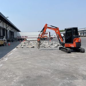 Excavator breaking up concrete pad